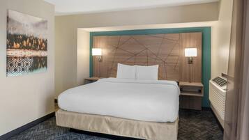 A hotel room with a large bed, two bedside tables, a wall-mounted lamp, and a radiator.