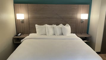 Una habitación de hotel con una cama grande, cabecera de madera con diseños geométricos, dos lámparas de noche y un teléfono junto a la cama.