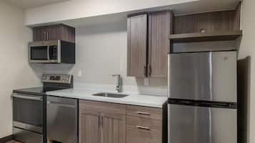 Una cocina moderna con electrodomésticos de acero inoxidable, armarios de madera y encimera blanca.