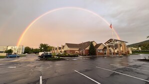 Un hôtel Best Western doté d’un parking et avec un arc-en-ciel en arrière-plan.