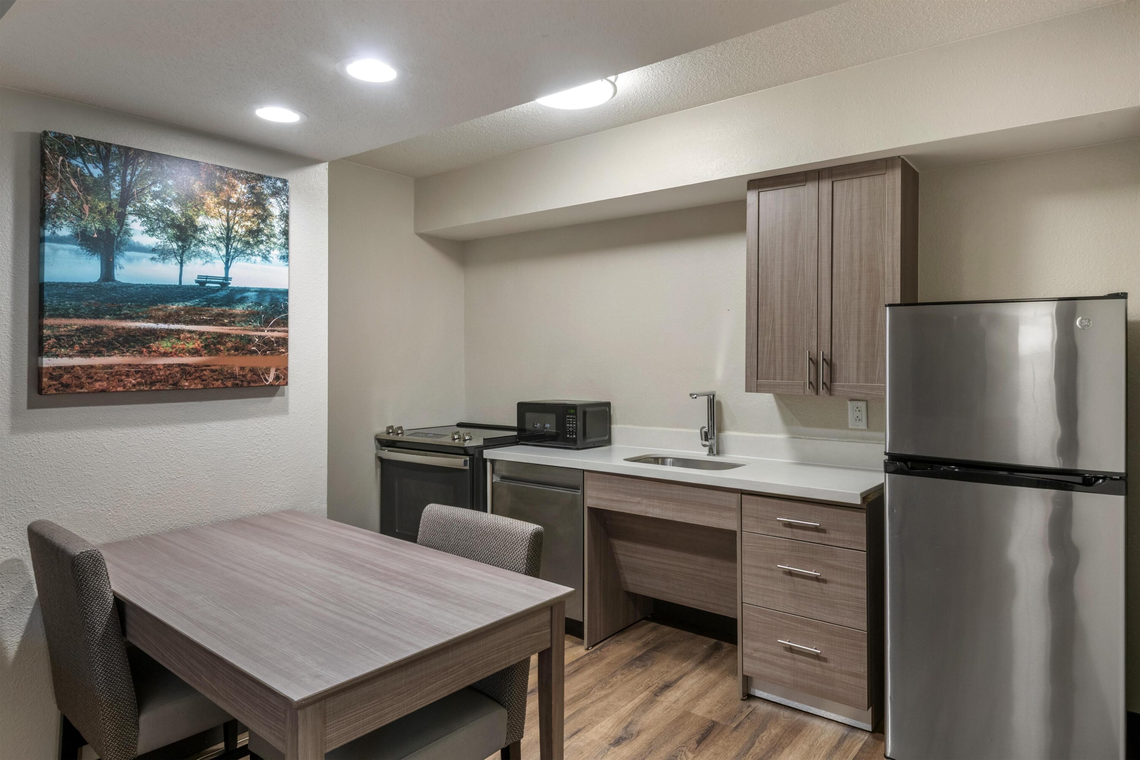 A modern kitchen with a dining table, built-in appliances, and a painting on the wall.