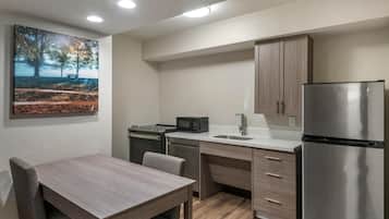 A modern kitchen with a dining table, built-in appliances, and a painting on the wall.