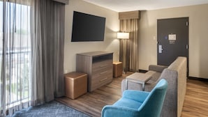 Une chambre d’hôtel équipée d’un téléviseur à écran plat, d’un canapé, d’une petite table, d’une lampe, d’une armoire et d’une porte.