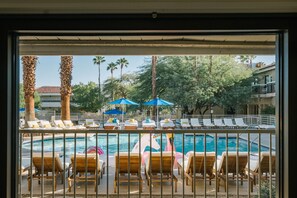 A poolside area with lounge chairs and umbrellas, surrounded by palm trees and a clear sky. - L3 Oasis Hotel (Palm Springs)