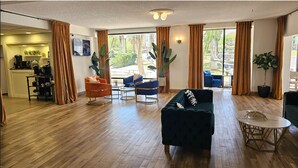 Amplia sala de estar con sofá, sillas, una mesa de centro y grandes ventanales con vistas al exterior.