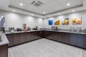 A modern kitchen with dark cabinets, a granite countertop, and various appliances. - Days Inn by Wyndham St. Louis Lindbergh Boulevard (St. Louis)