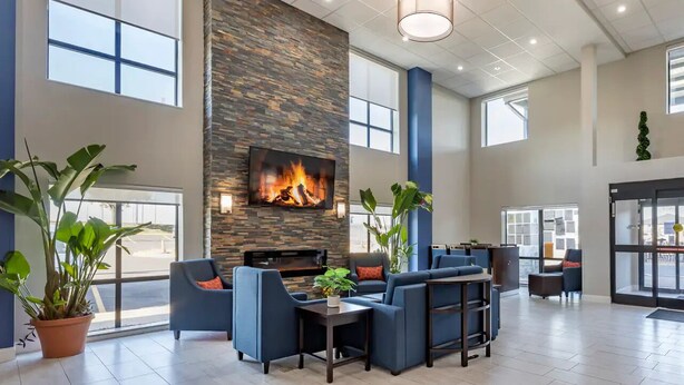 A spacious lobby with a stone fireplace, comfortable seating, large windows, and a flat-screen TV. - Days Inn by Wyndham St. Louis Lindbergh Boulevard (St. Louis)