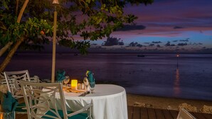 A table set for dining with a view of the ocean at dusk. - Mango Bay All Inclusive (Holetown)