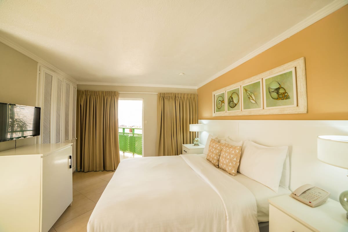 A hotel room with a bed, a desk, a television, a telephone, and a window with curtains.
