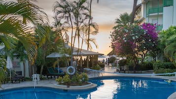 Een buitenzwembad, parasols bij het zwembad en ligstoelen