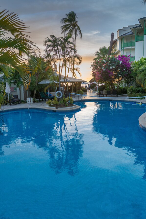 Una piscina al aire libre, sombrillas, tumbonas