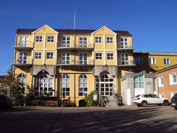 A multi-story hotel with a yellow facade, balconies, and a sign indicating it's a Best Western hotel.