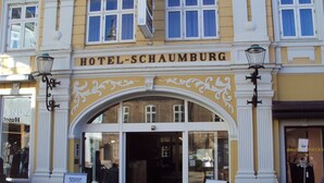 Een hotelentree met een bord waarop 'HOTEL-SCHAUMBURG' staat.