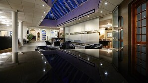 Een ruime lobby met een centraal zitgedeelte, een glazen plafond en een receptiebalie.