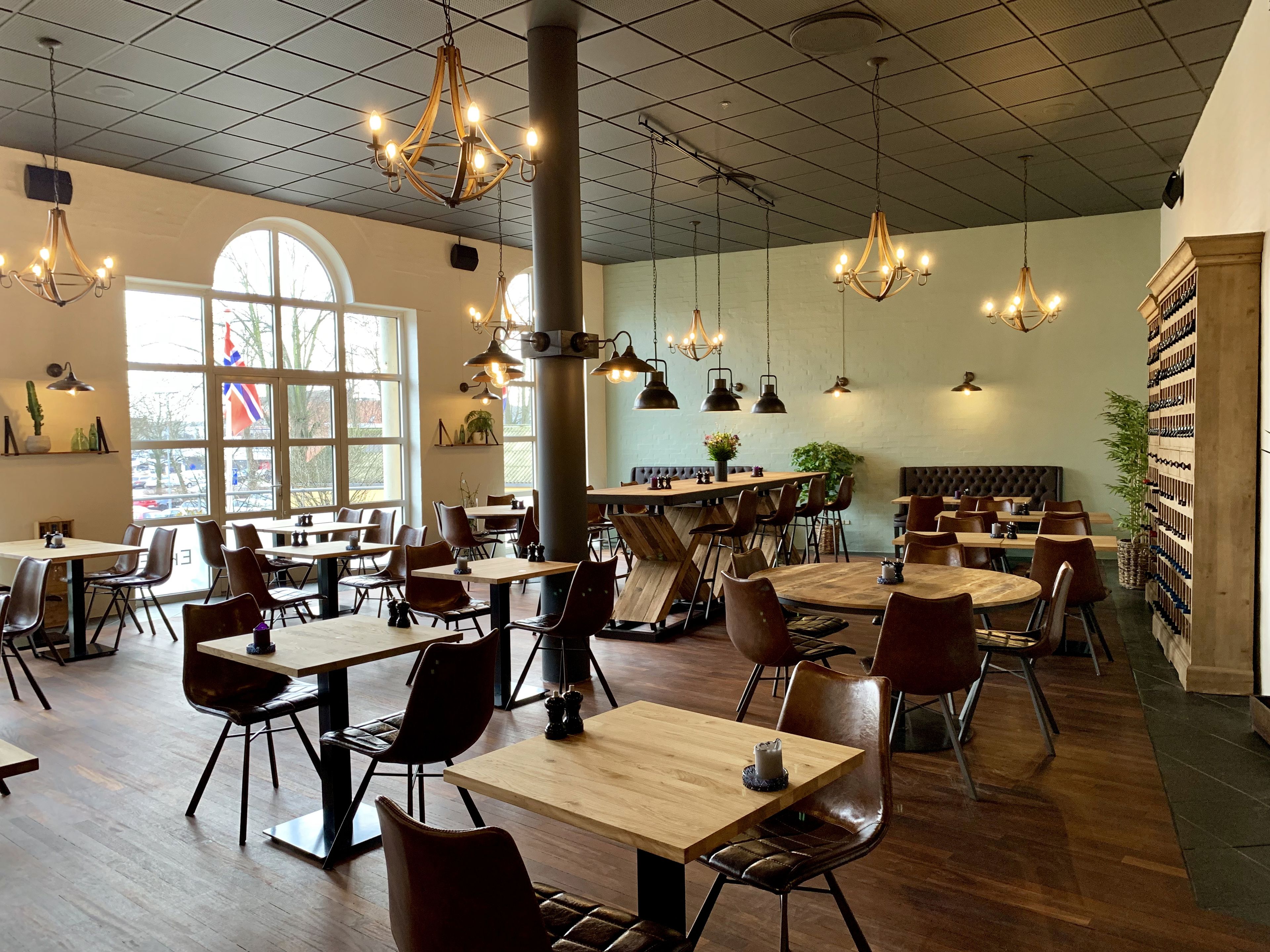 A spacious restaurant with high ceilings, multiple chandeliers, and a variety of seating arrangements including tables and booths.