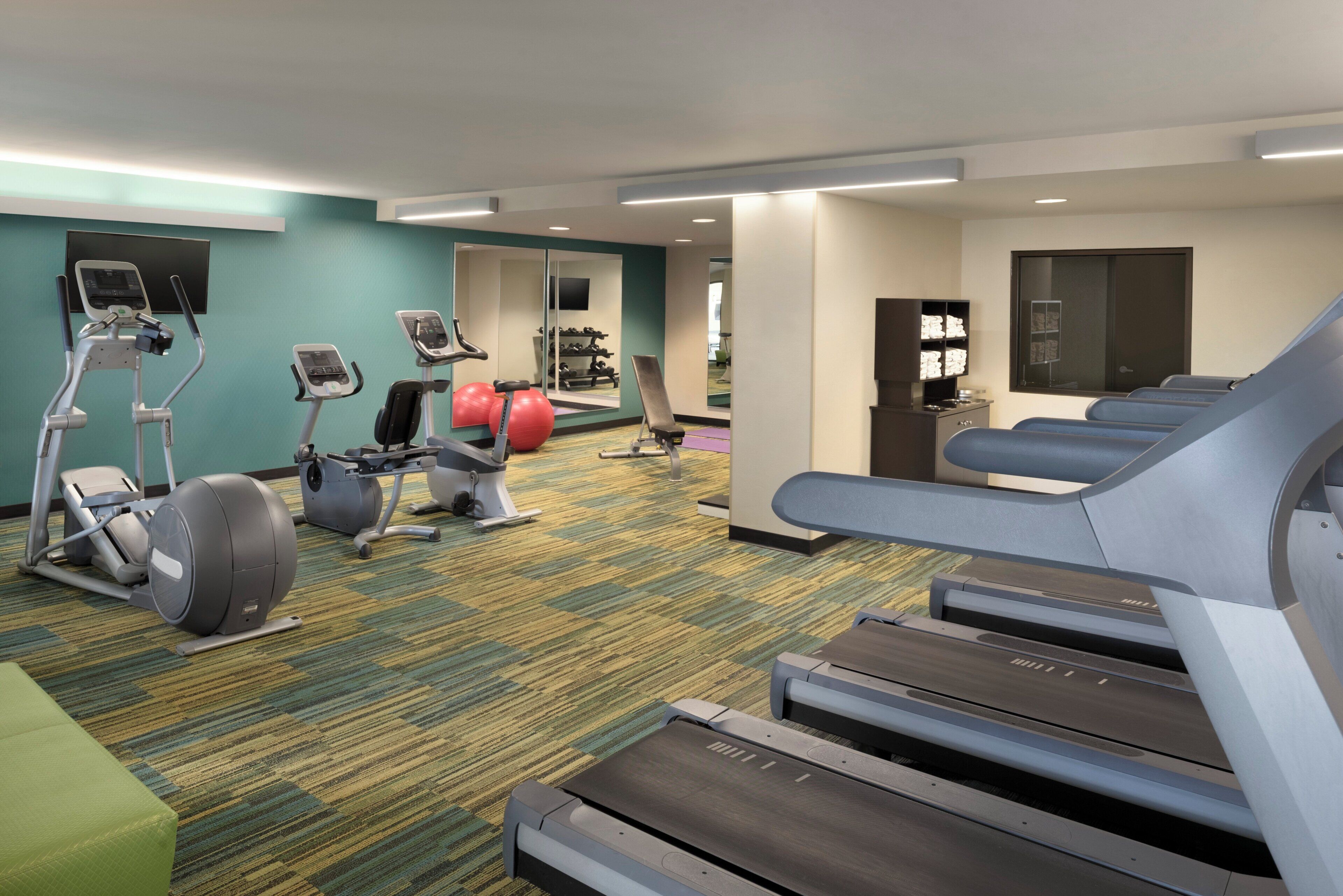 A hotel fitness center with treadmills, elliptical machines, and exercise balls.