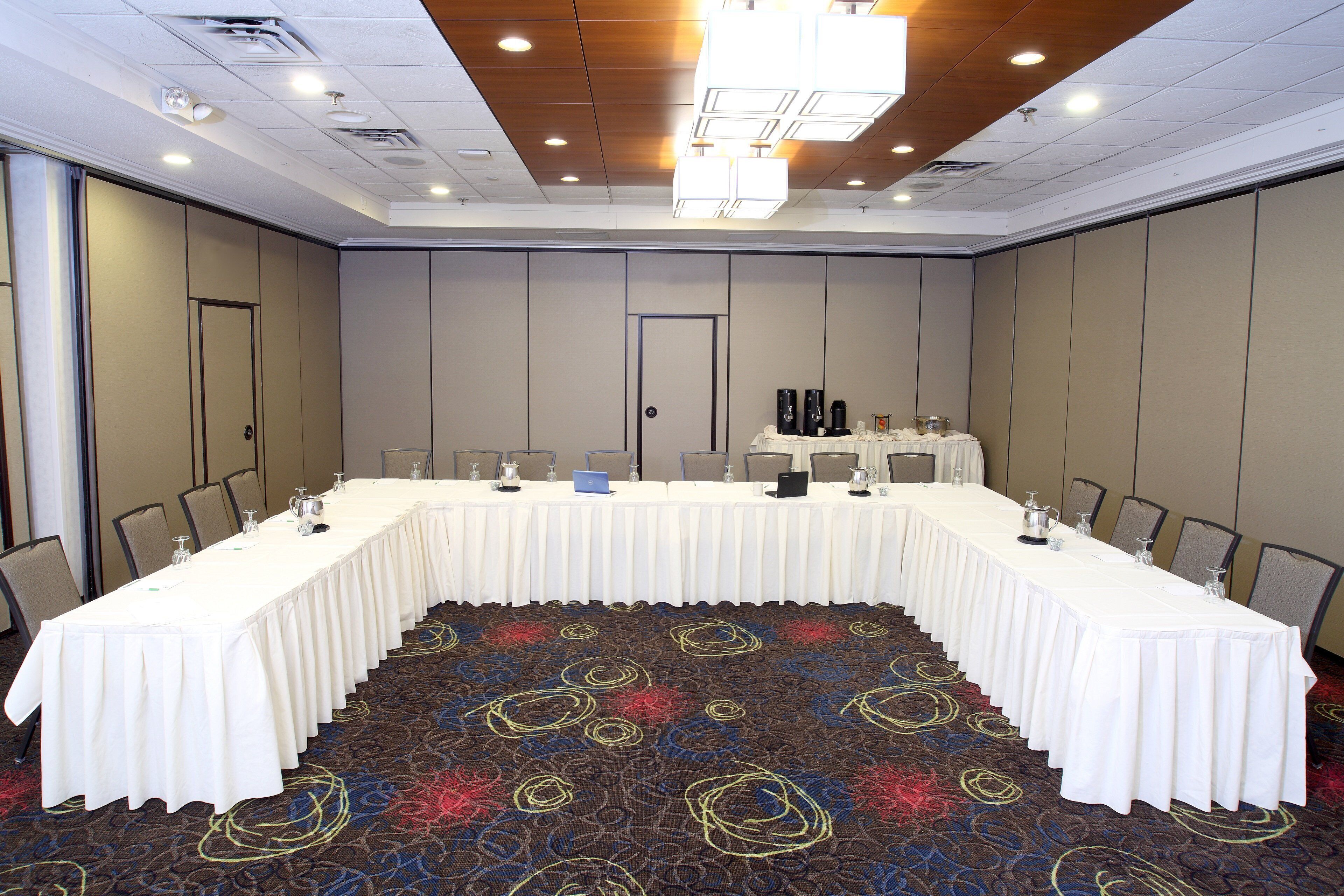 Un salón de conferencias con una larga mesa, sillas y piso alfombrado.