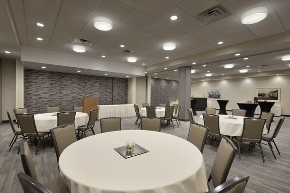 A conference room with round tables, chairs, and a stone wall.
