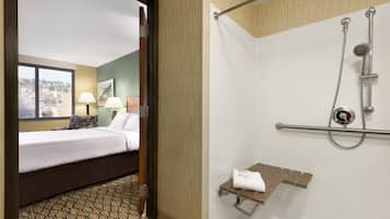 Hotelkamer met een bed, een raam met uitzicht, een douche met handgreep en een handdoekhouder.