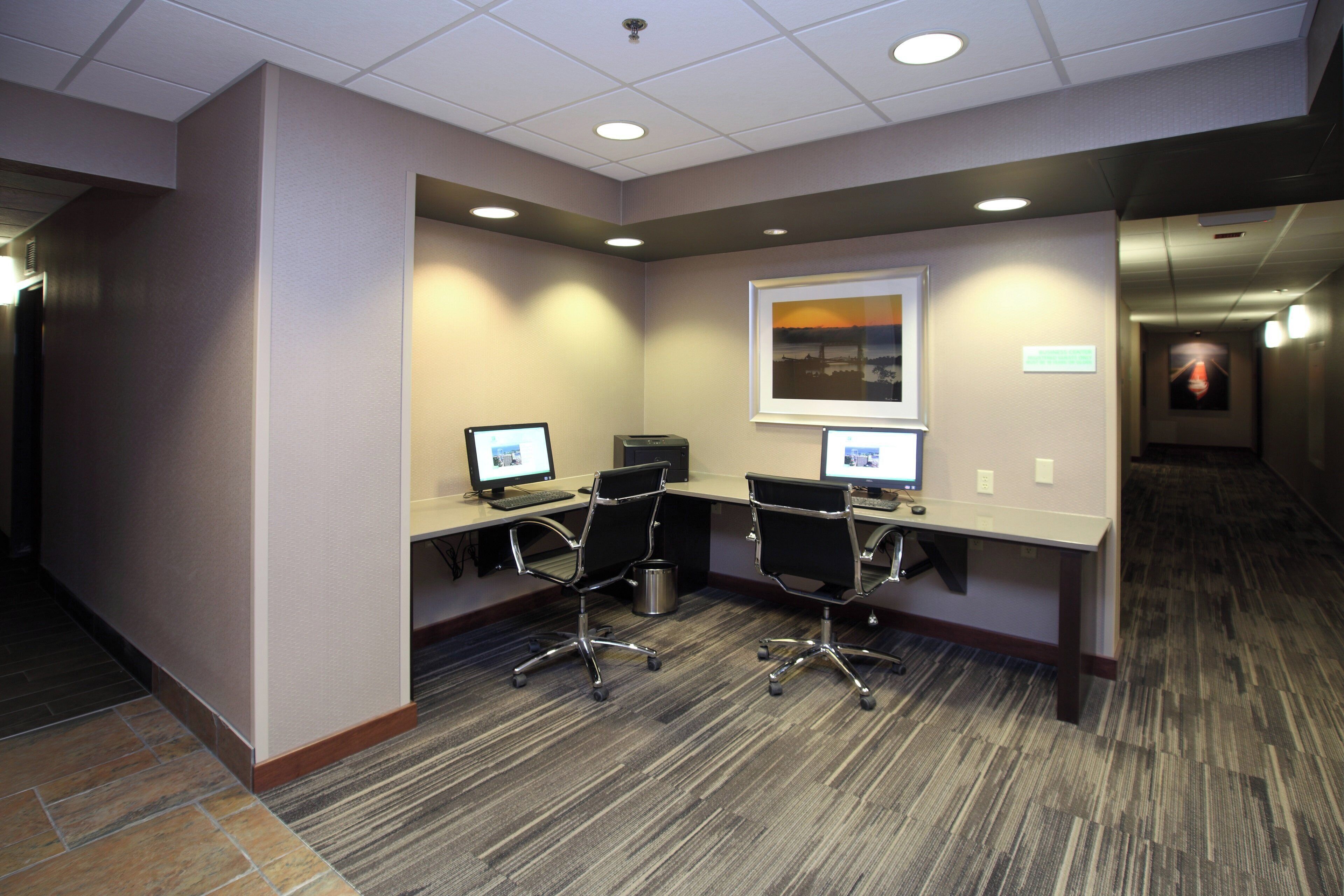 A conference room with two desks, chairs, and computers.