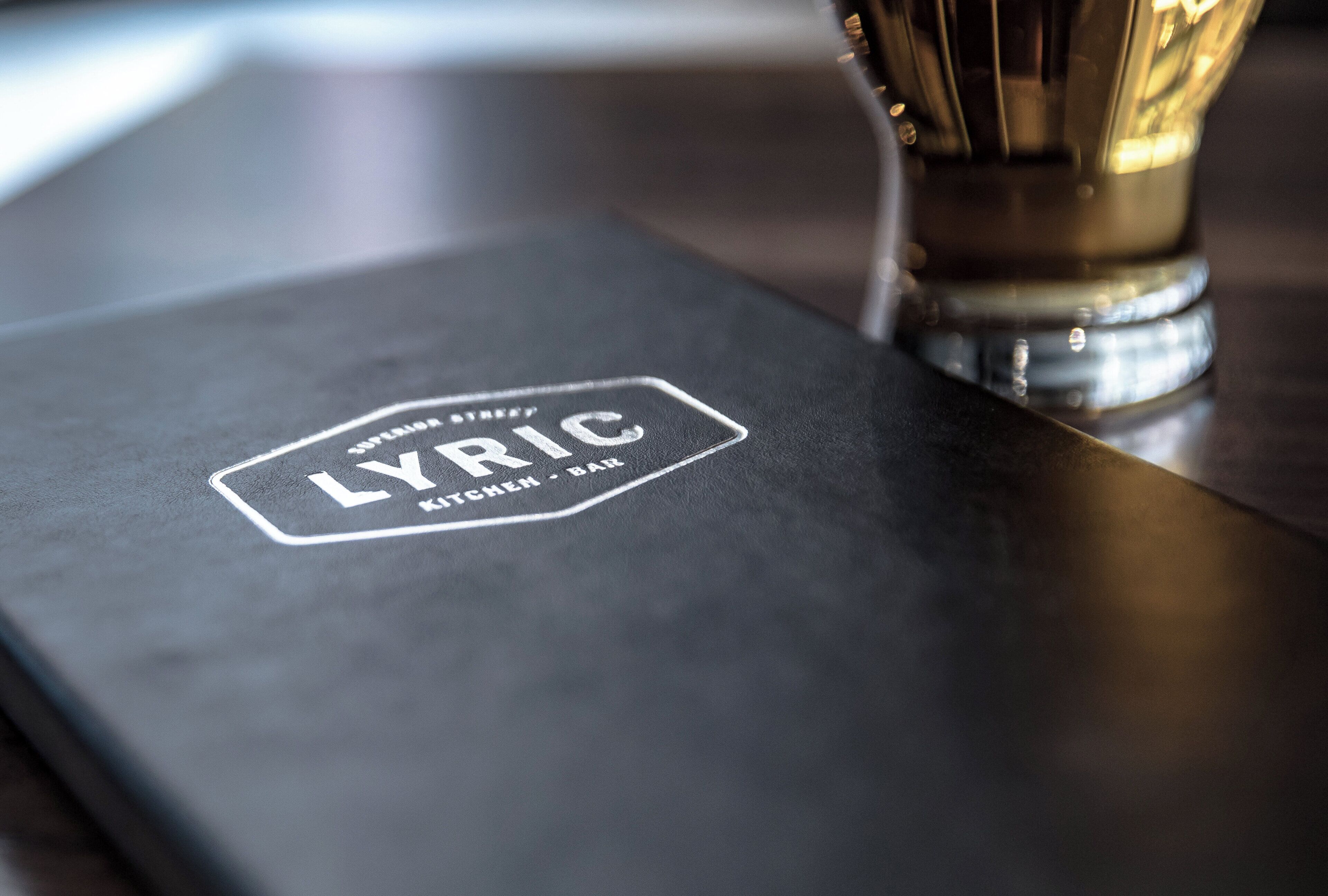 A black surface with embossed text 'LYRIC KITCHEN BAR' indicating a restaurant or bar area.