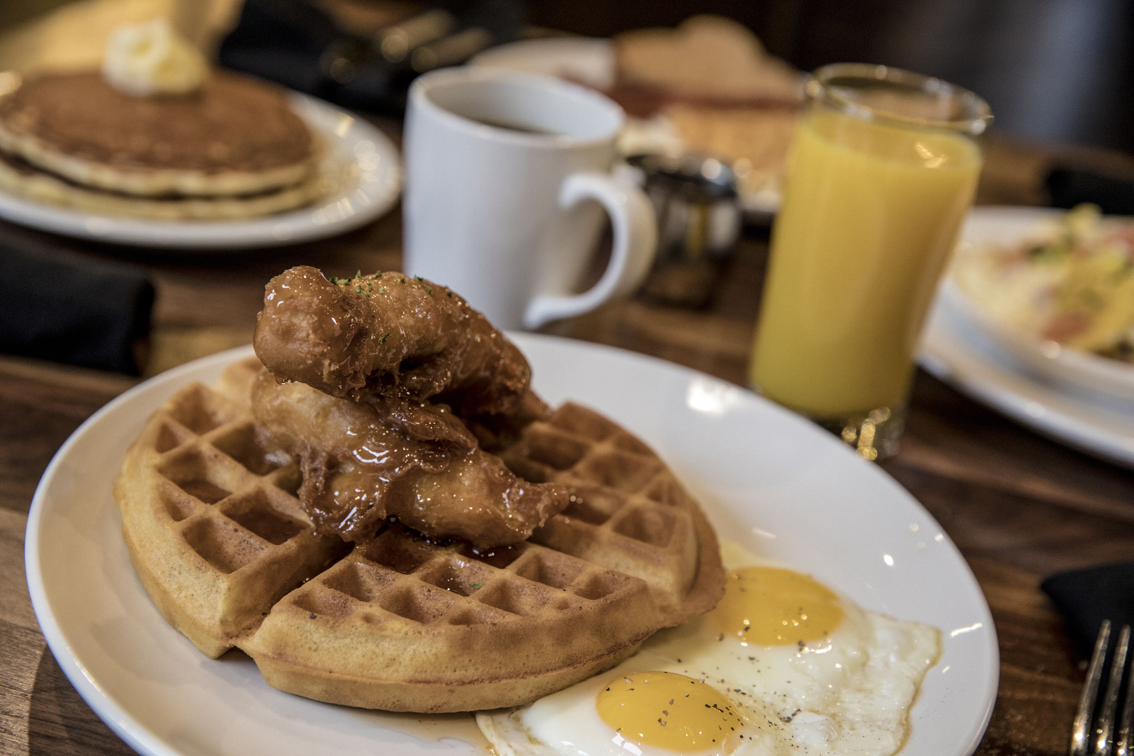 A breakfast plate with waffles, fried chicken, and eggs.