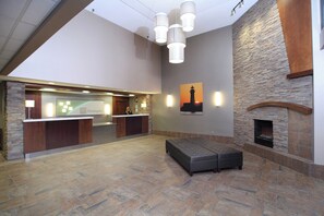 Un hall d’entrée avec un comptoir de réception, une cheminée et un espace salon.