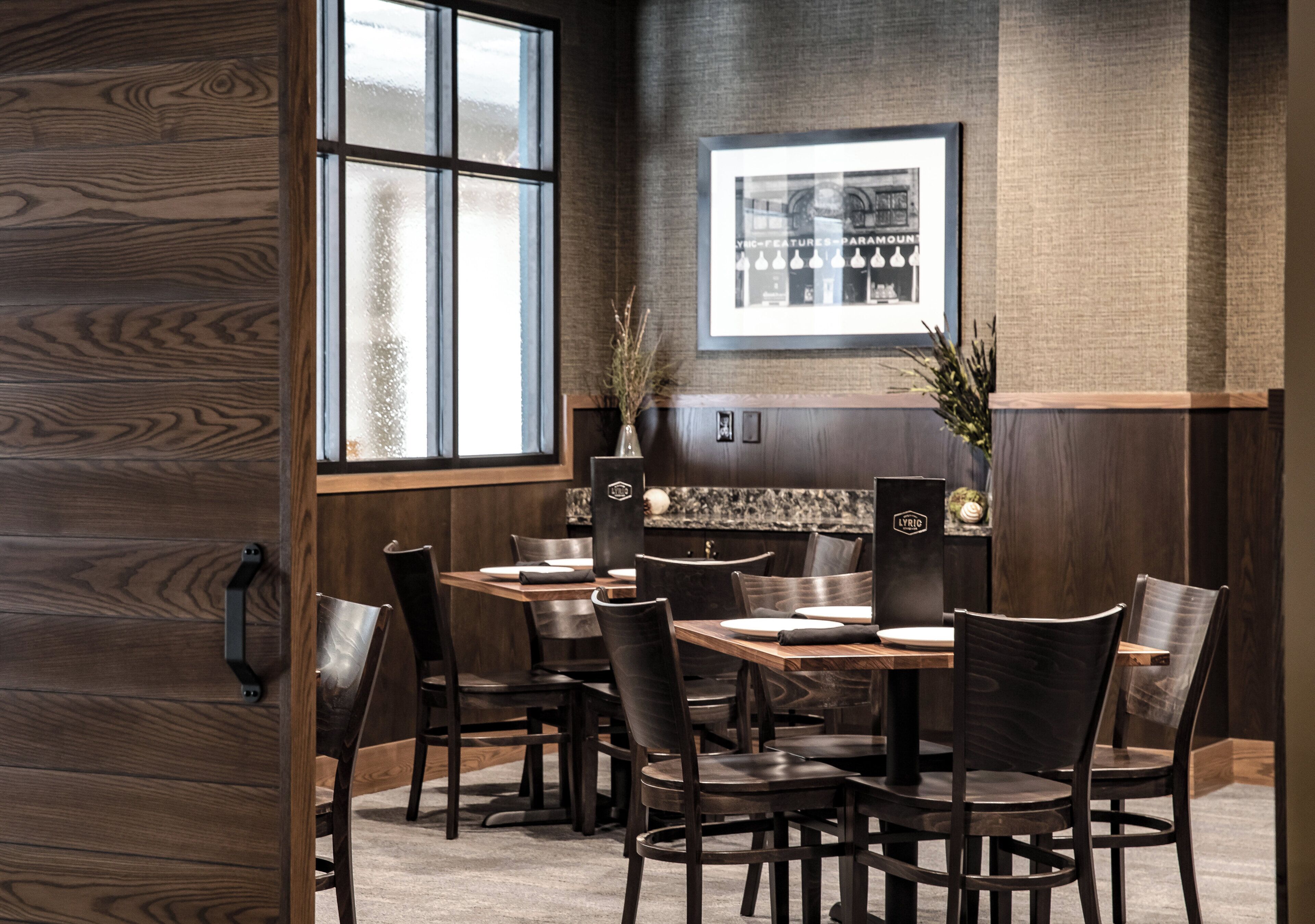 Interno di un ristorante con parete rivestita in legno, un'ampia finestra e un quadro appeso.