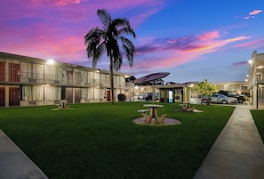 A hotel with a well-maintained lawn, outdoor seating, and a parking area.