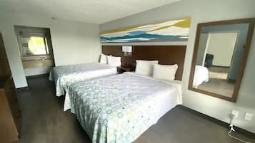 Una habitación de hotel con dos camas, un cuadro grande en la pared y un espejo.
