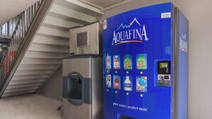 Un dispensador de agua con etiqueta azul y un refrigerador de acero inoxidable.
