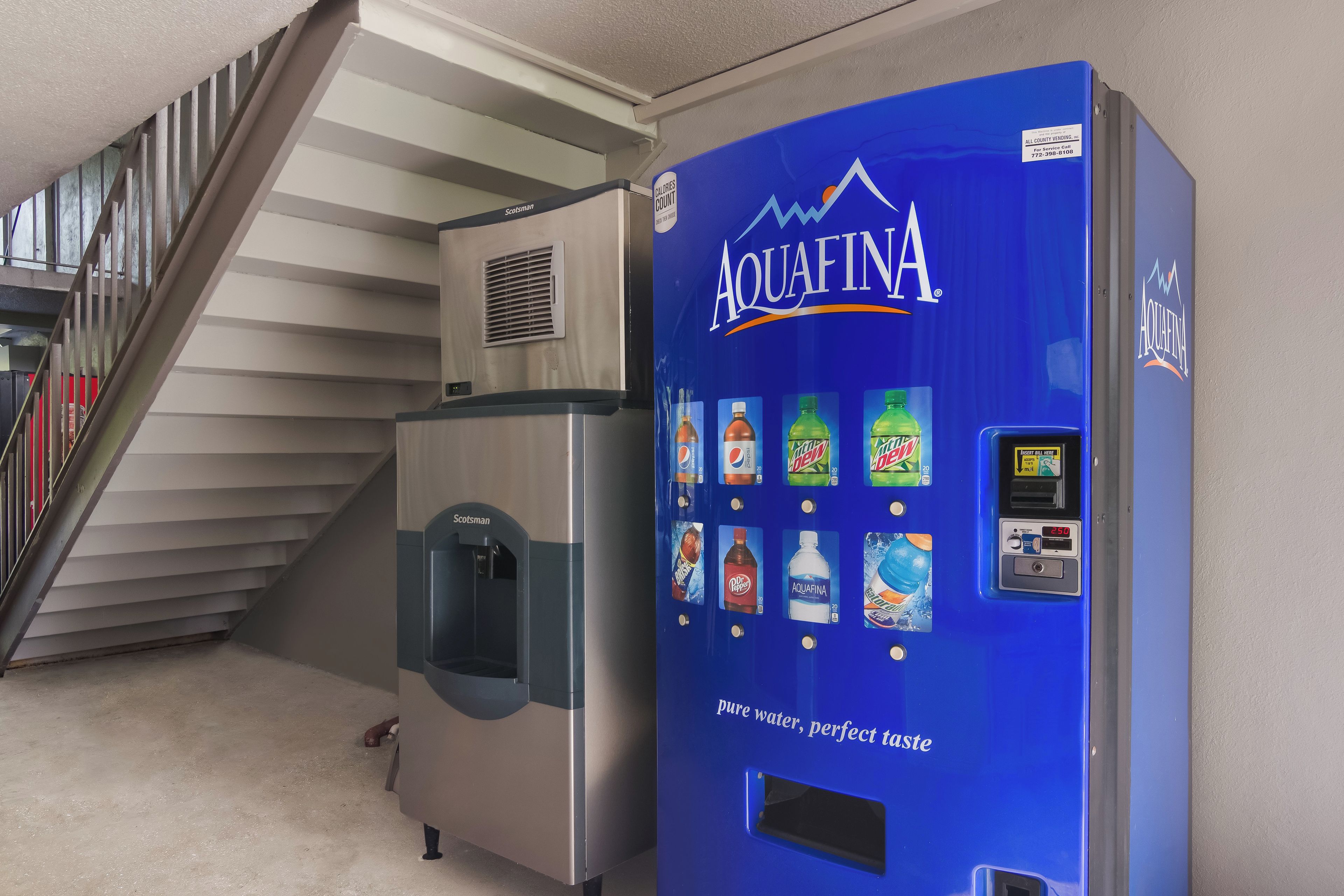 A water dispenser with a blue label and a beverage vending machine with various drink options.