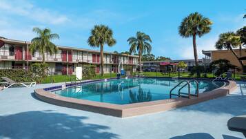 Una piscina al aire libre, sombrillas, sillones reclinables de piscina