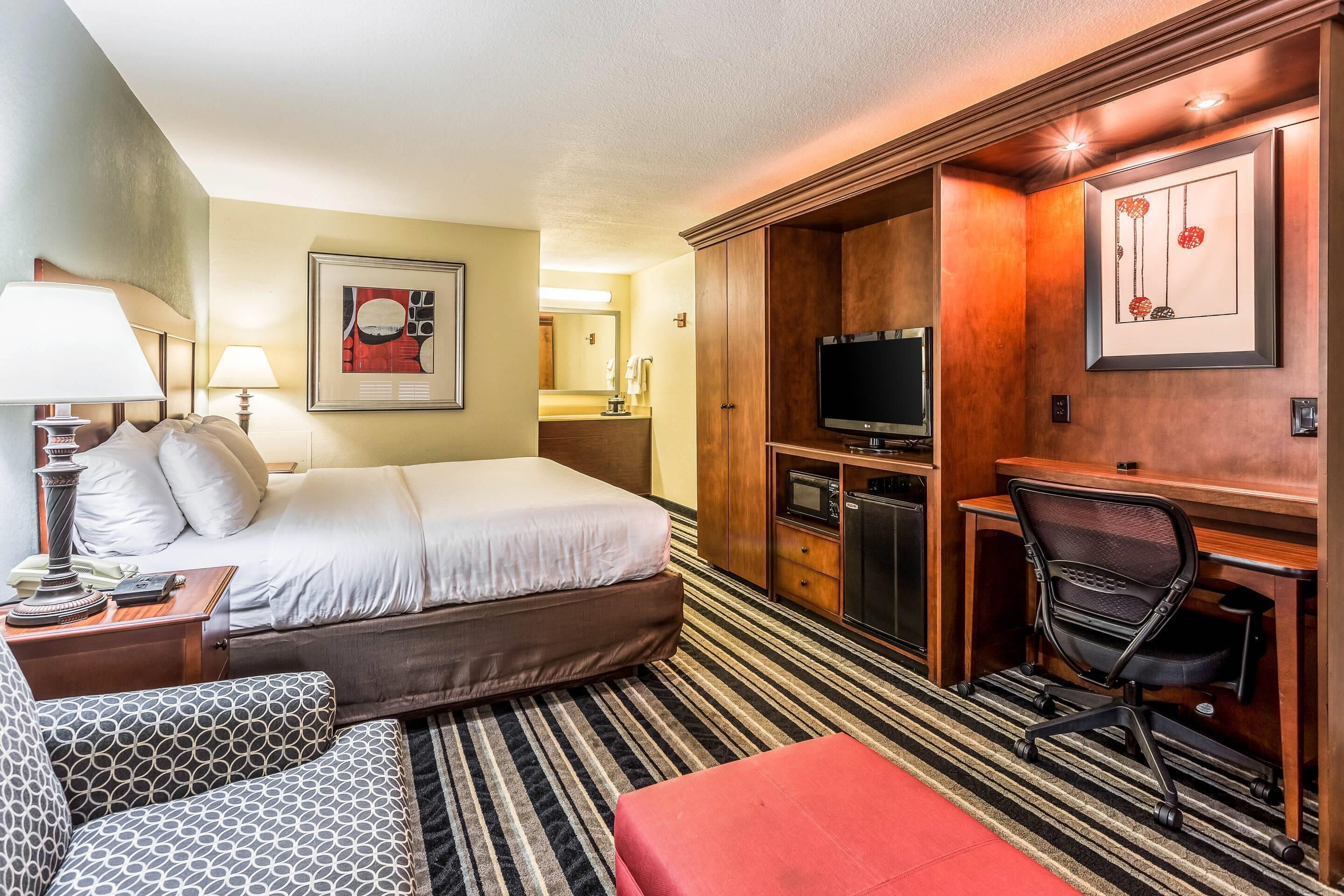 Une chambre d’hôtel comprenant un lit, un bureau avec une chaise, une télévision et une kitchenette.