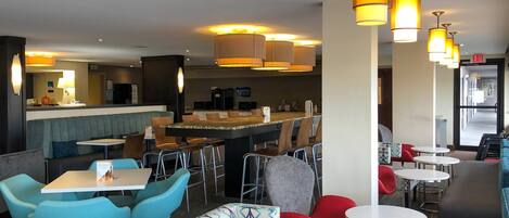 A modern restaurant with a bar area, seating arrangements, and overhead lighting.
