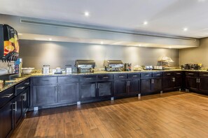 A modern kitchen with dark cabinetry, a granite countertop, and a built-in coffee station.