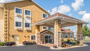 A hotel with a covered entrance, a flag, and a landscaped area with plants. - Comfort Inn Ottawa Starved Rock Area (Ottawa)