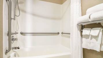 A bathroom with a bathtub, grab bars, a towel rack, and a shower curtain.