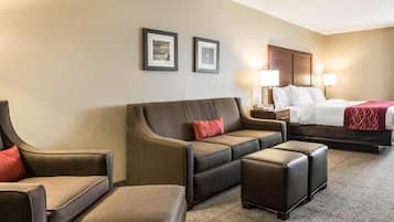 Ein Hotelzimmer mit einem Bett, einer Couch, zwei Sesseln und einem kleinen Tisch.
