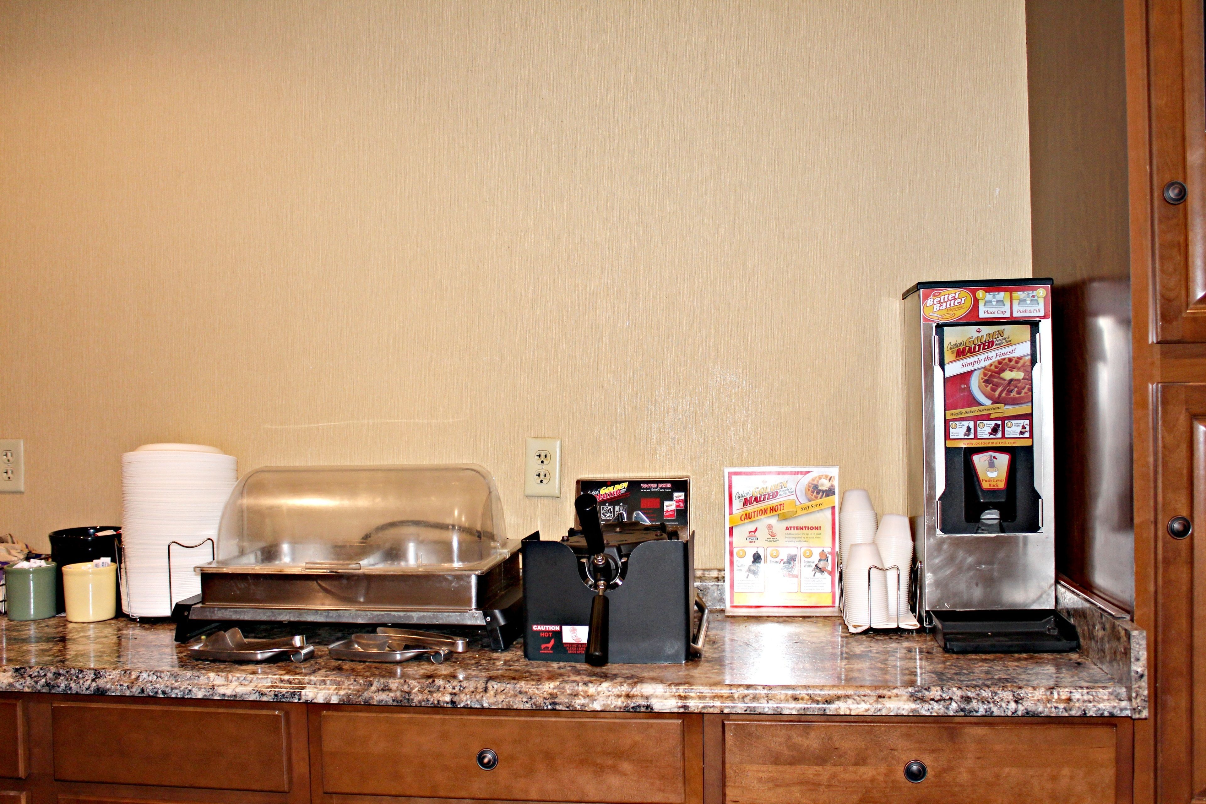 A kitchen counter with a coffee machine, a food warmer, and a beverage dispenser.