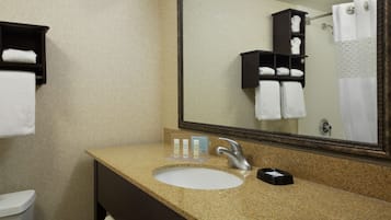 Een badkamer met een wastafel, spiegel, handdoekrek en toiletartikelen.