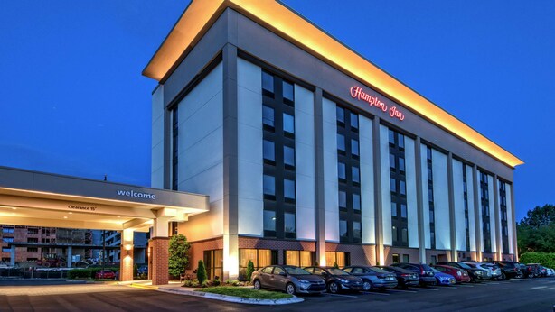 A Hampton Inn hotel with a clear entrance, a parking lot with several cars, and a well-lit facade. - Hampton Inn Charlotte - University Place (Charlotte)