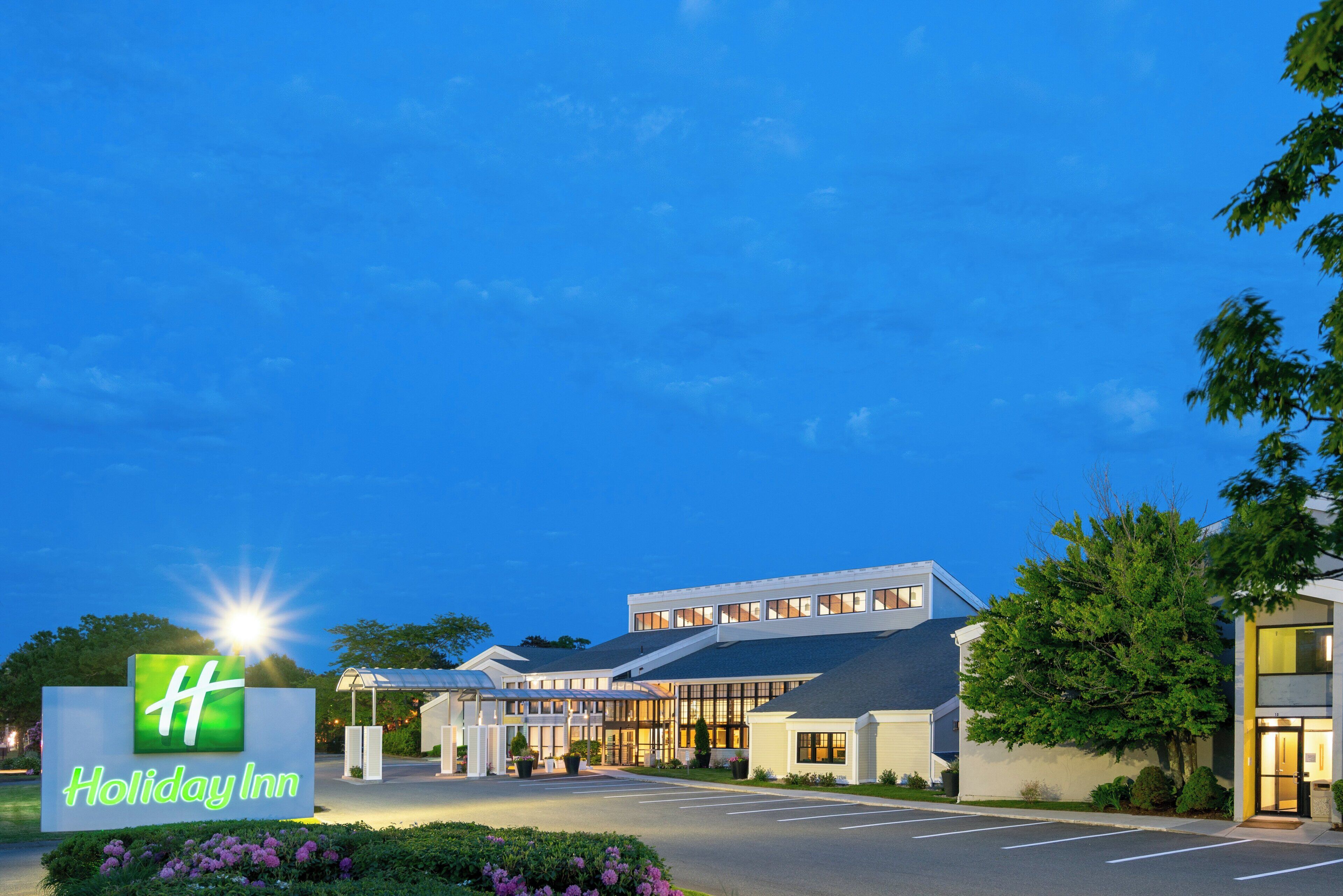 Een Holiday Inn hotel met een modern design, met een ruime parkeerplaats en een goed onderhouden tuin.