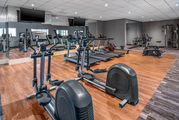 A gym with various cardio and strength training equipment, including treadmills, elliptical machines, and weight machines.