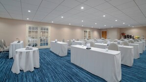 A conference room with multiple tables and chairs, equipped with microphones and projectors.