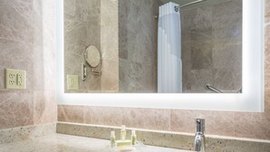 A bathroom with a large mirror, a sink, and a shower area. - Holiday Inn Hyannis by IHG (Hyannis)