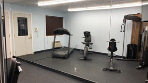Une salle de sport équipée d’un tapis de course, d’un vélo d’appartement et d’une machine de musculation.