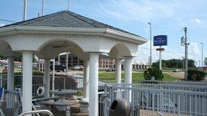 Un kiosque doté d’un toit blanc et de colonnes, entouré d’une clôture en métal.