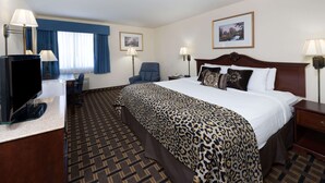 Une chambre d’hôtel avec un grand lit, un bureau avec un ordinateur, une chaise et deux lampes.