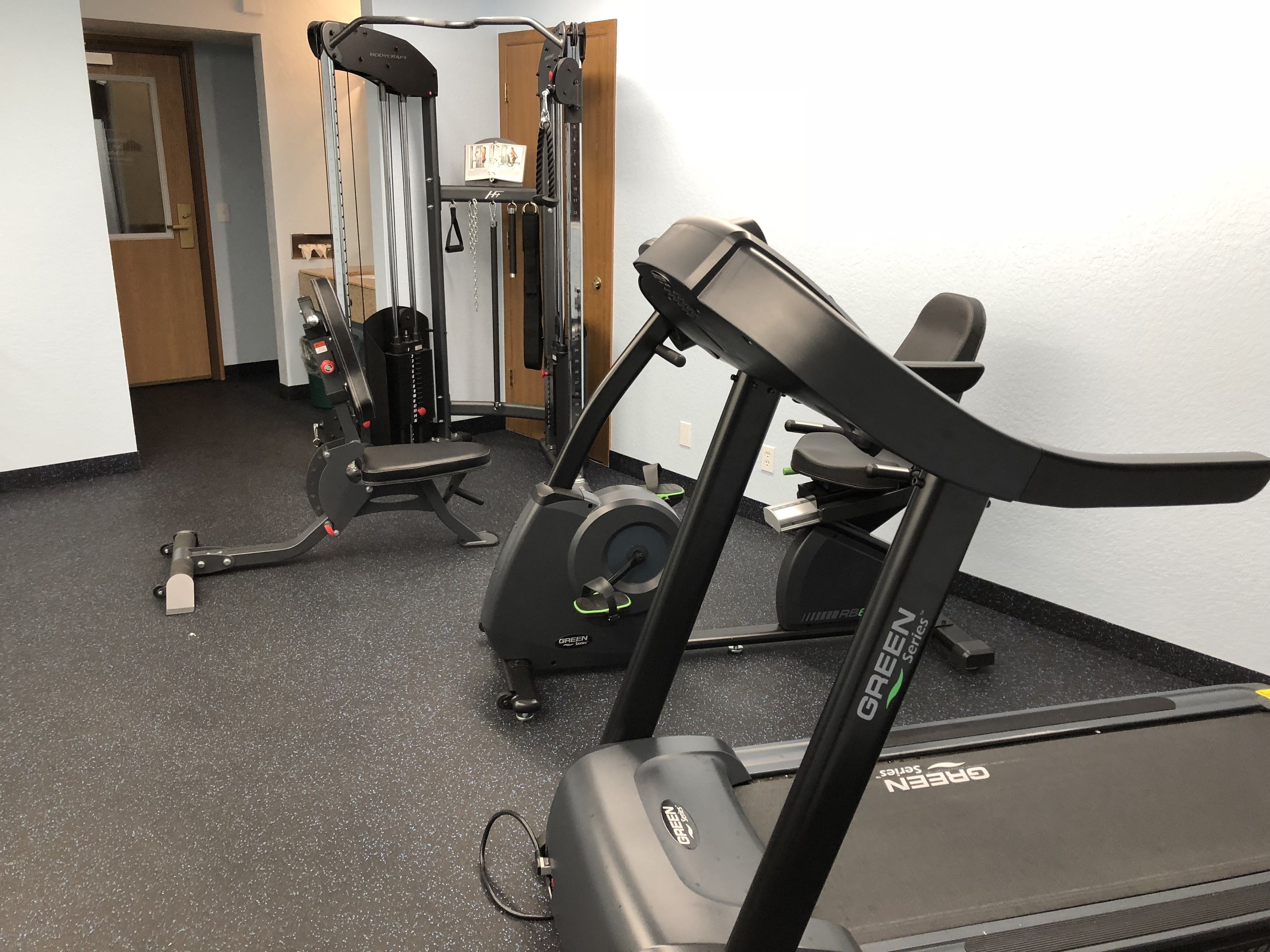 A gym with a treadmill, weight machines, and a bench.